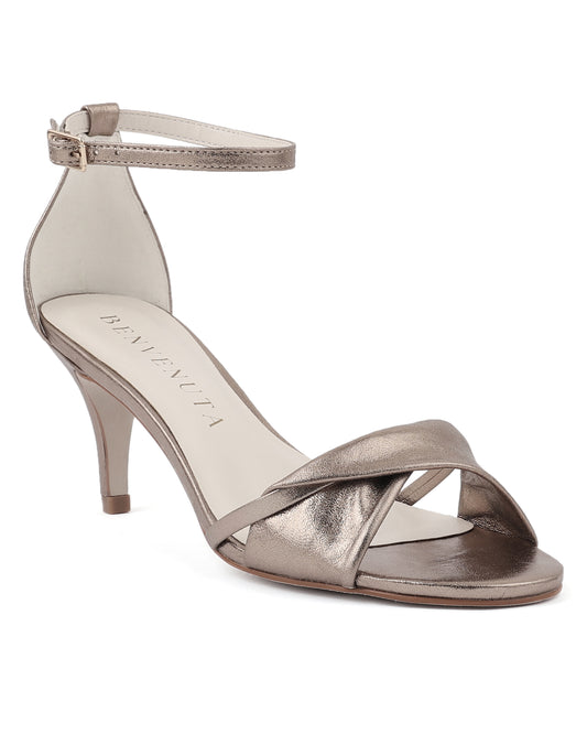 Sandália Vera 70 prata velho com acabamento metalizado e salto fino de 7 cm. Sapato de festa versátil em tom neutro, com tira torcida e fecho no tornozelo.