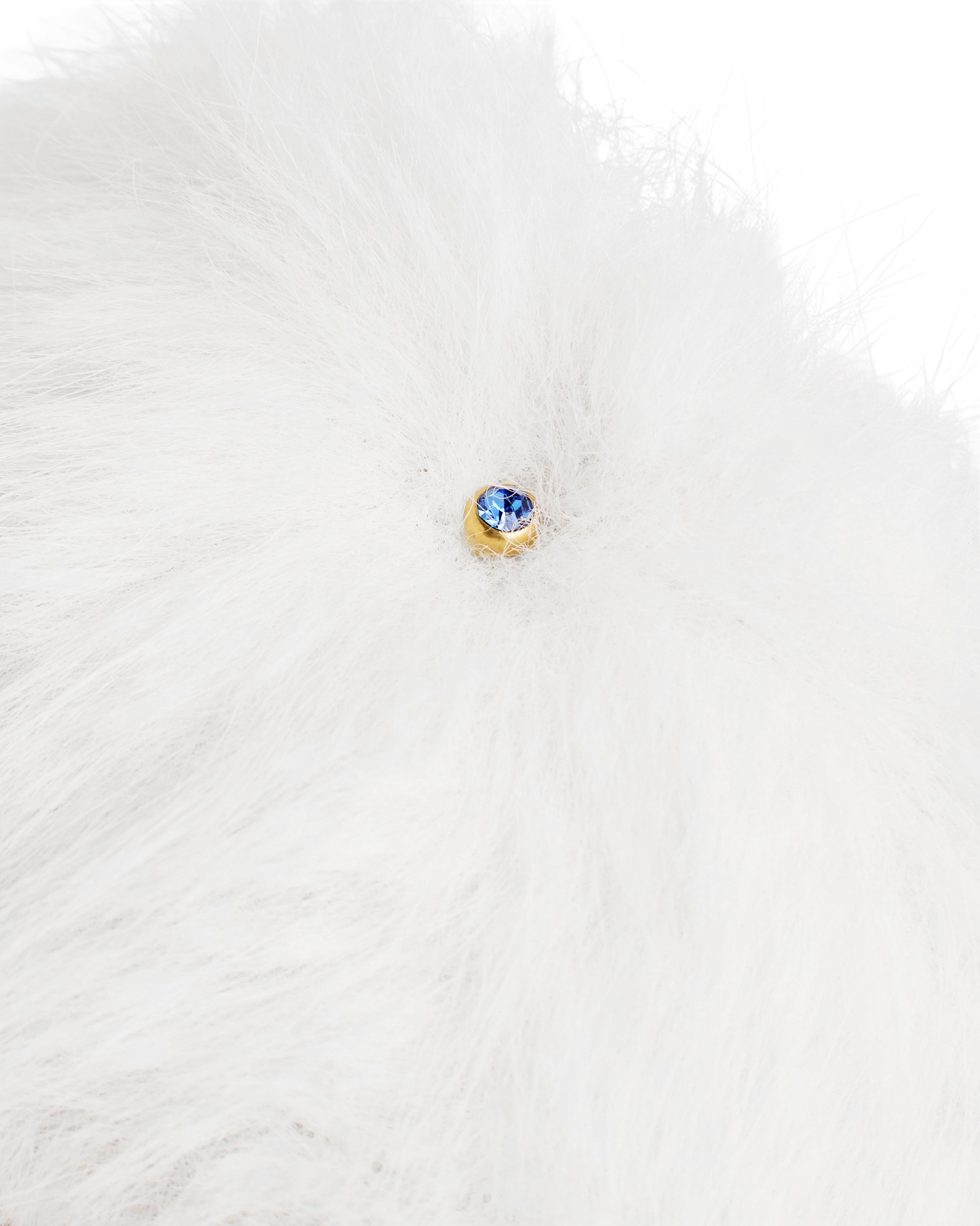 Detalhe do pingente em cristal azul na faixa de pelo branco do chinelinho da linha Serenitá Benvenuta.