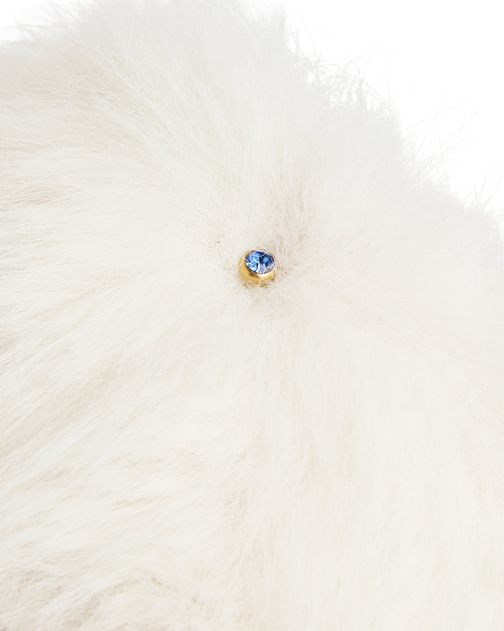 Detalhe do pingente em cristal azul na faixa de pelo creme do chinelinho da linha Serenitá Benvenuta.